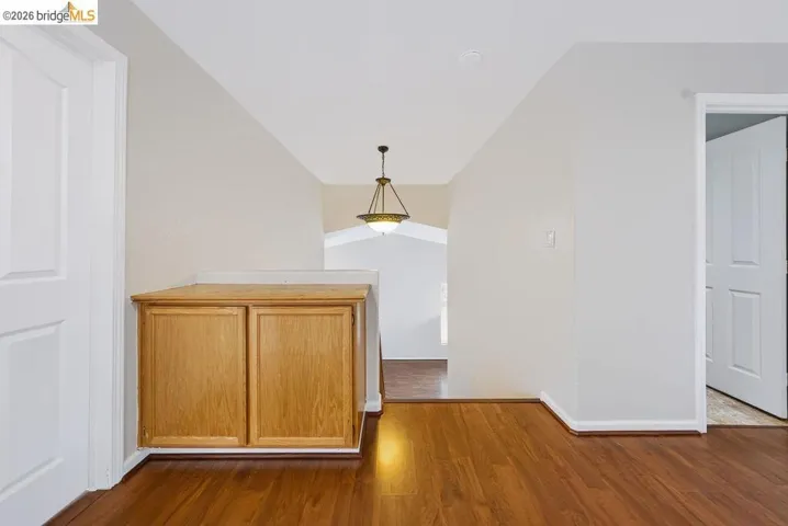 Hallway featuring wood-finish flooring, built-in cabinetry, and a decorative ceiling fixture