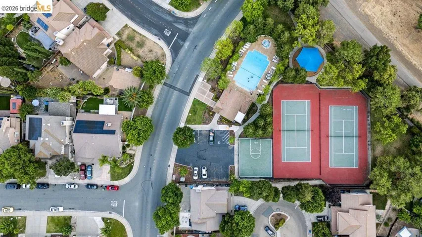 Aerial view showcasing community amenities including two tennis courts, a basketball court, and a swimming pool with a spa