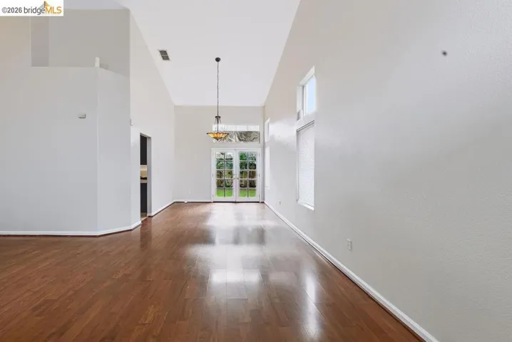 Expansive living space featuring high vaulted ceilings, rich wood-finish flooring, and bright white walls