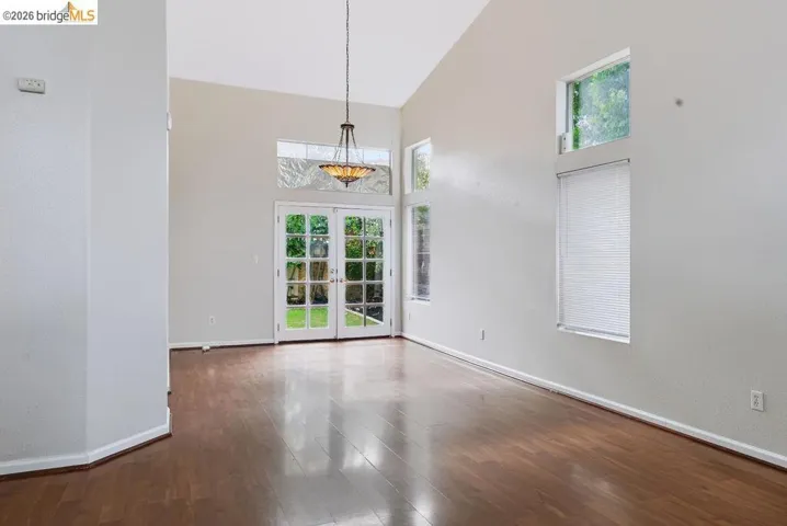 Living area featuring high vaulted ceilings, wood-finish flooring, and white walls