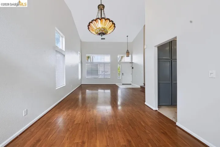 Vaulted ceilings with decorative chandeliers, wood-finish flooring, and multiple windows providing natural light
