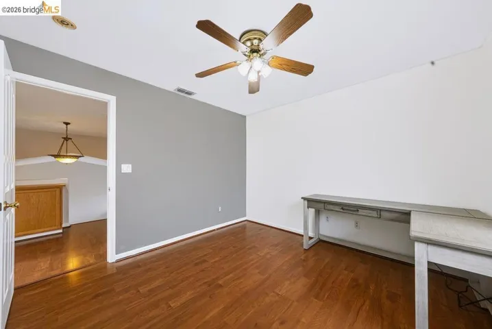Interior room featuring wood-finish flooring, a ceiling fan with integrated lighting, and a recessed ceiling light