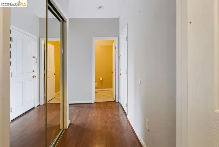 Hallway featuring wood-finish flooring, light gray wall paint, and white trim