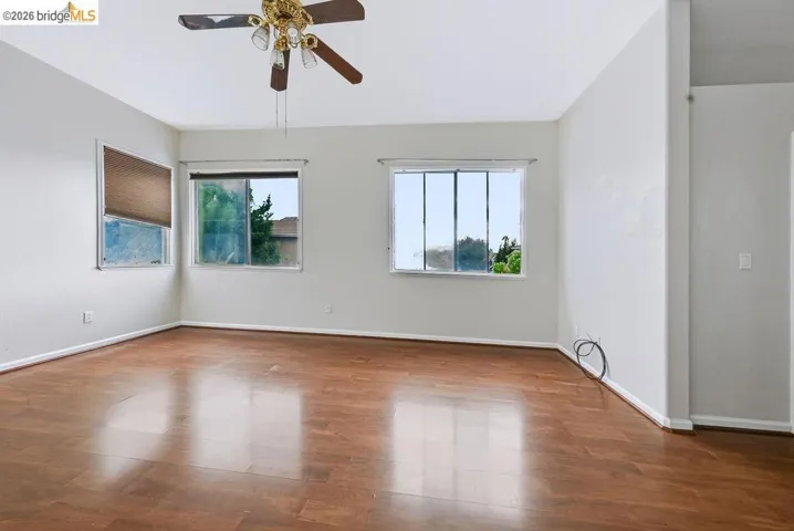 Spacious room featuring wood-finish flooring, light-toned walls, and multiple windows