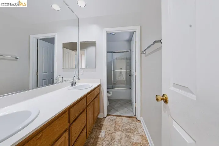 Bathroom featuring a dual-sink vanity with wood cabinetry and white countertops