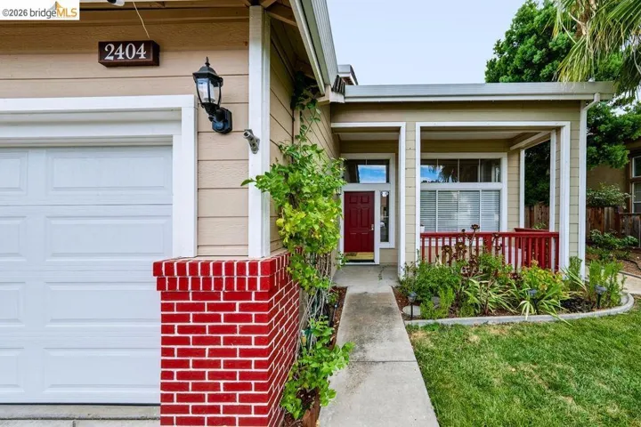 Front exterior with a red entry door, covered porch, and a garage with a white panel door