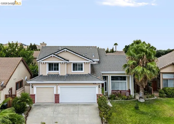 Two-story residence featuring a two-car garage, concrete driveway, and a front porch with a red railing