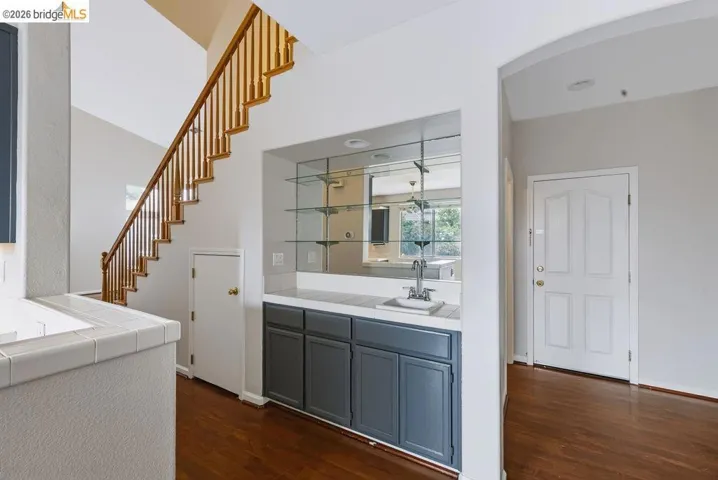 Integrated wet bar with gray base cabinetry, white countertop, and mirrored backsplash