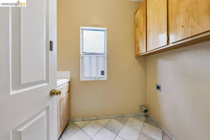 Utility room featuring upper wood cabinetry, a built-in counter, and a window for natural light