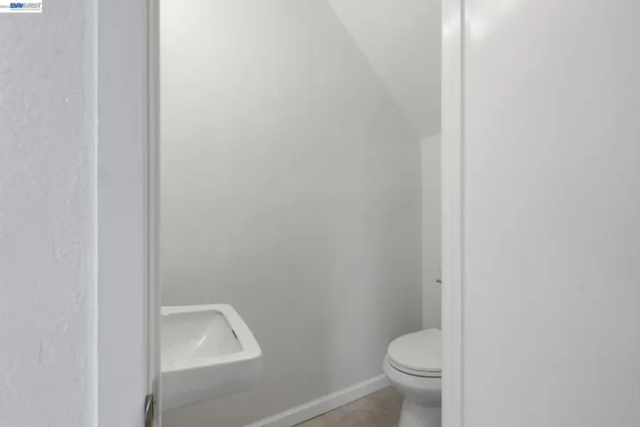 Compact powder room featuring a wall-mounted sink, a white toilet, and light-toned flooring