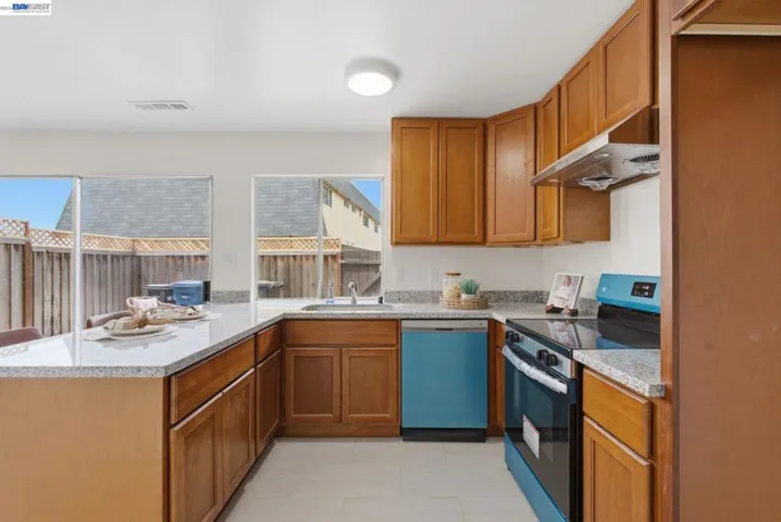 Open-concept kitchen featuring wood cabinetry, light-toned countertops, and a full suite of appliances