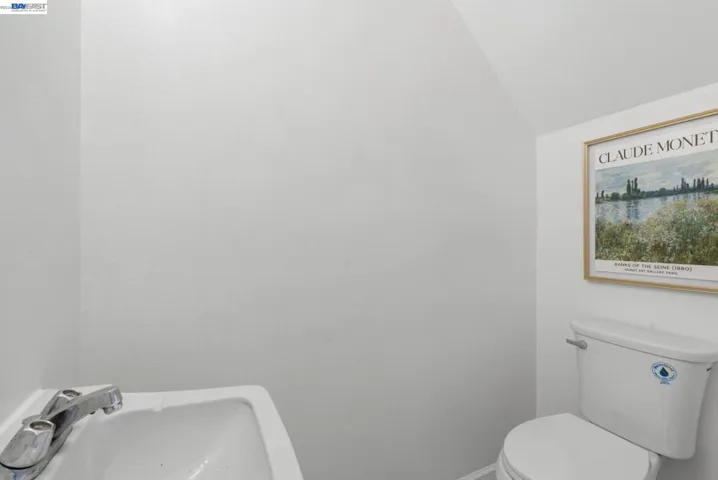 White powder room featuring a wall-mounted sink with chrome faucet and a white toilet