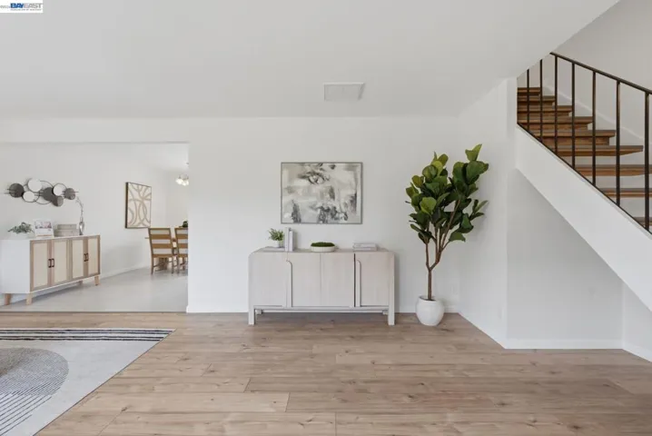 Hardwood-style flooring throughout, featuring a staircase with wood treads and black metal railings