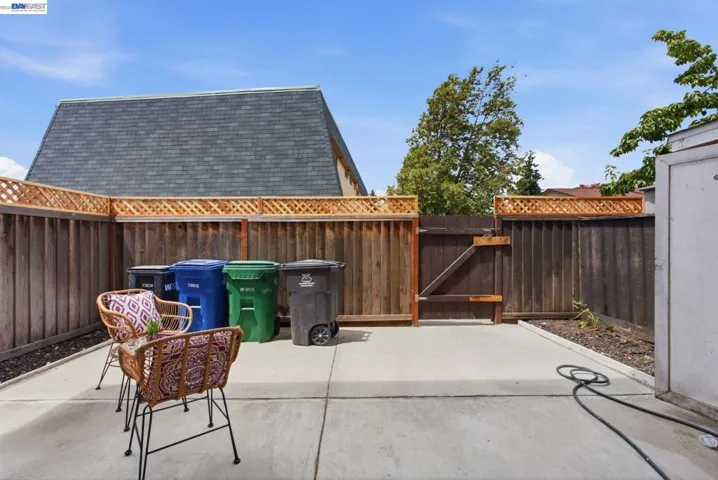 Concrete patio area featuring a wooden fence with lattice top, and a private side gate