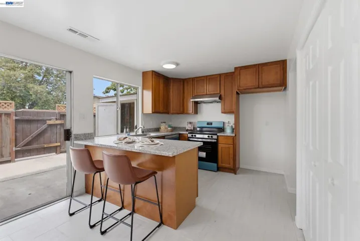 Kitchen featuring wood cabinetry, granite-style countertops, stainless steel sink, and a built-in oven with range hood