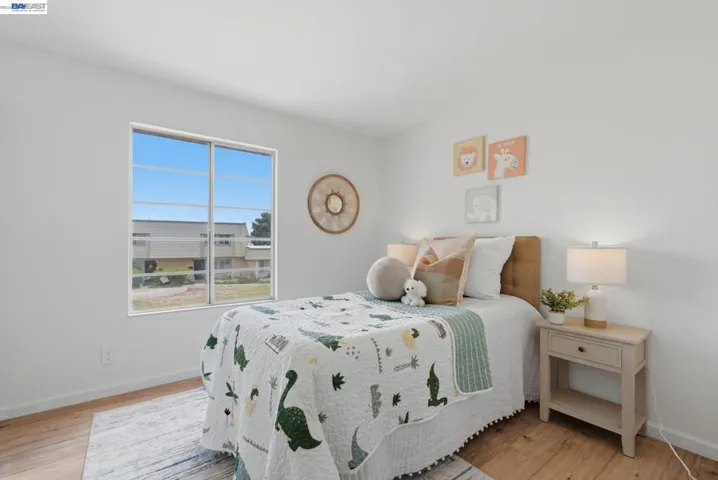Bedroom featuring a large sliding window, light wood-finish flooring, and white painted walls