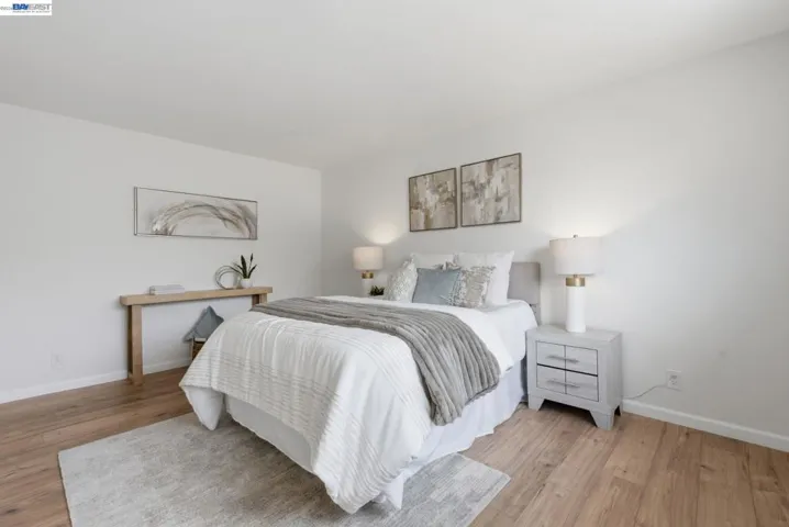 Bedroom featuring wood-finish flooring, light-toned walls, and a recessed baseboard