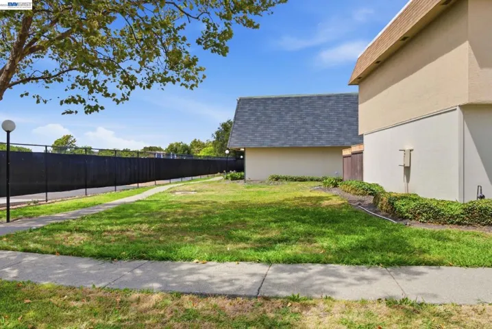 Expansive grassy area featuring a concrete sidewalk and mature landscaping