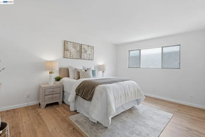 Bright room featuring light-toned wood-finish flooring, white walls, and a horizontal window with blinds