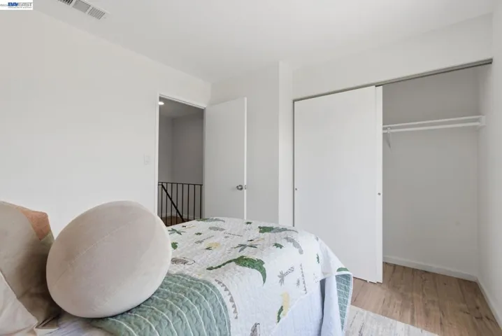 Bedroom featuring wood-finish flooring, a white bi-fold closet, and white walls