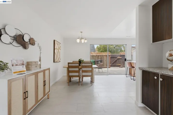 Open-concept dining area featuring light tile flooring and a contemporary chandelier