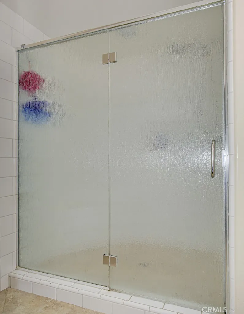 Oversized shower in primary bathroom has a convenient seat and accessory shelf.