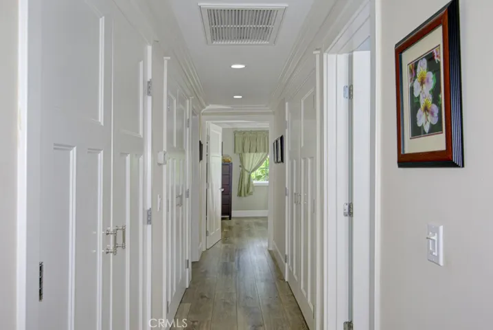 Hallway leading to bedrooms and bathrooms. There is a large closet on the lefthand side extending the length of the hallway that currently serves as a pantry.