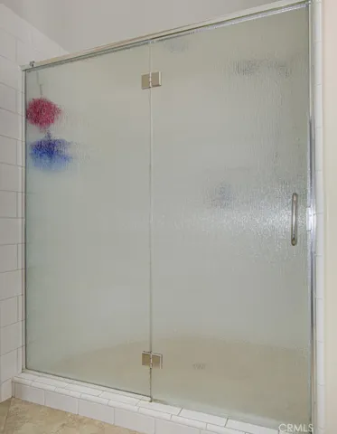 Oversized shower in primary bathroom has a convenient seat and accessory shelf.