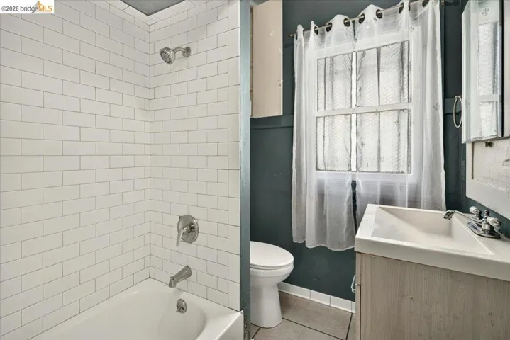 Bathroom featuring a white subway tile shower surround, a white bathtub, and a vanity with a rectangular sink