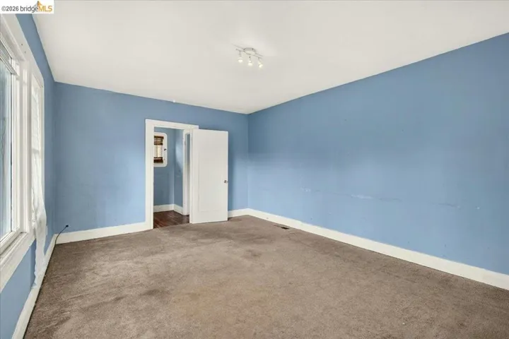Spacious room featuring light blue walls, white trim, and a neutral-toned carpet
