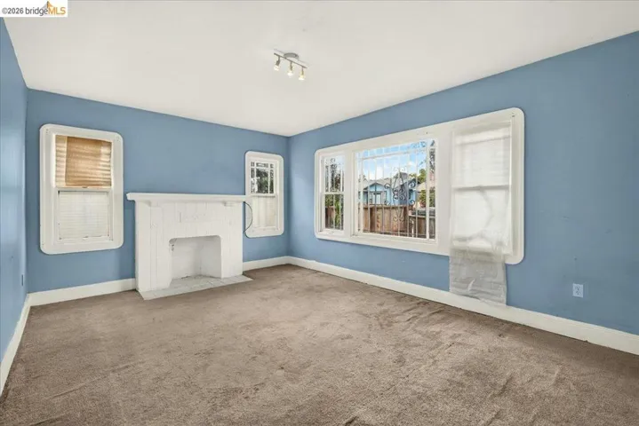 Spacious interior with blue walls and a white ceiling, featuring a prominent white brick fireplace
