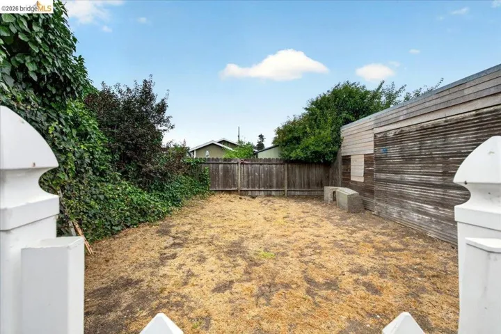 Enclosed yard area with a partial privacy fence and mature perimeter foliage