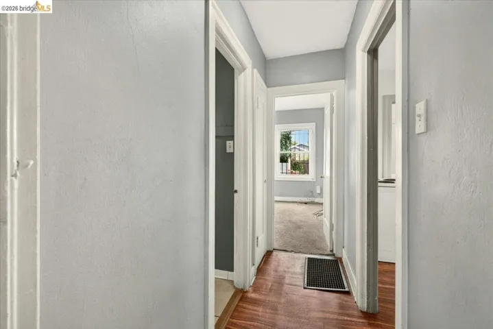 Hallway featuring wood-finish flooring, light gray wall paint, and white trim