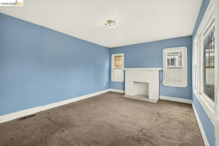 Room featuring a decorative fireplace with a white mantel, multiple windows, and track lighting