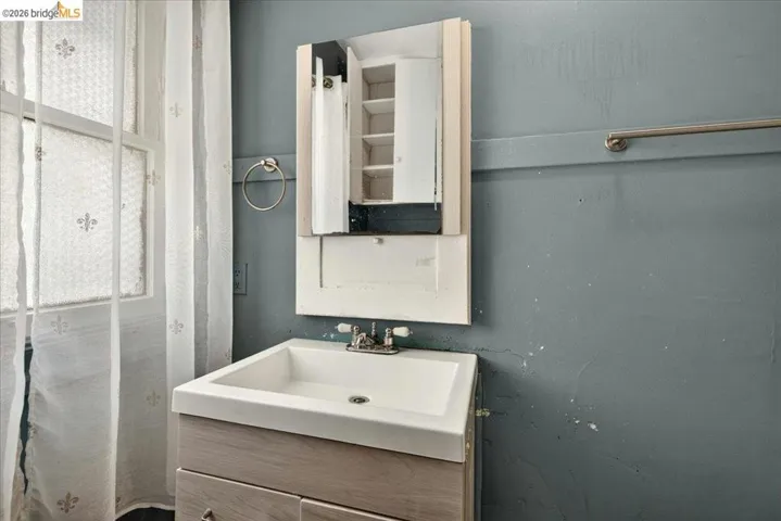 Bathroom featuring a white integrated sink, wood-finish vanity, and a mirrored medicine cabinet