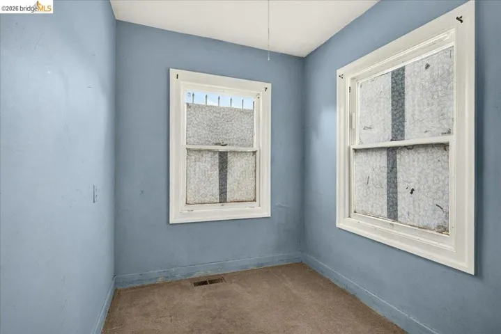 Room with two windows featuring white trim, blue walls, and carpet flooring
