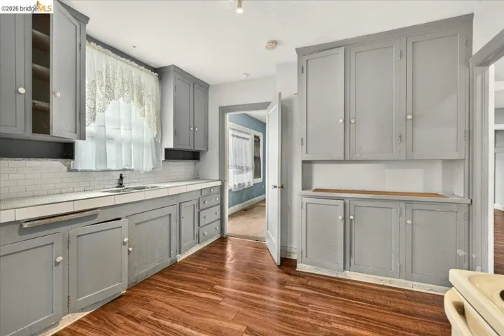 Kitchen featuring wood-finish flooring, light gray cabinetry, white tile countertops, and a white subway tile backsplash