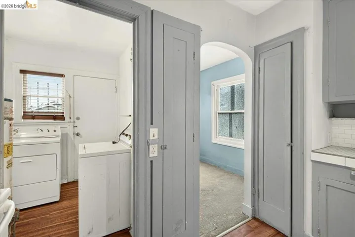 Dedicated utility area featuring wood-finish flooring, a window with horizontal blinds, and a solid exterior door