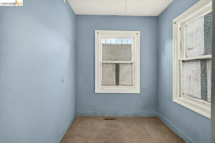 Interior room with two white-framed windows, light blue wall paint, and beige carpet flooring