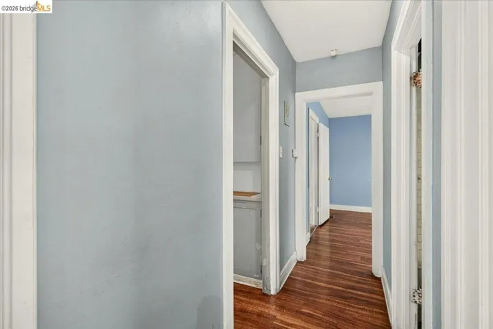 Hallway featuring wood-finish flooring, light blue walls, and white trim