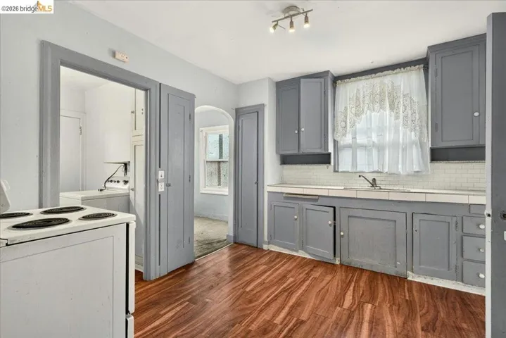 Kitchen featuring wood-finish flooring, gray cabinetry, white subway tile backsplash, and track lighting