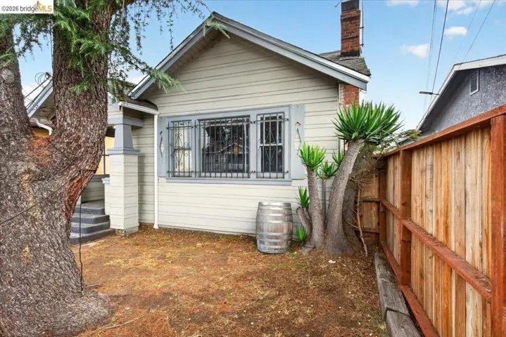 Exterior featuring horizontal siding, a prominent brick chimney, and a wooden privacy fence