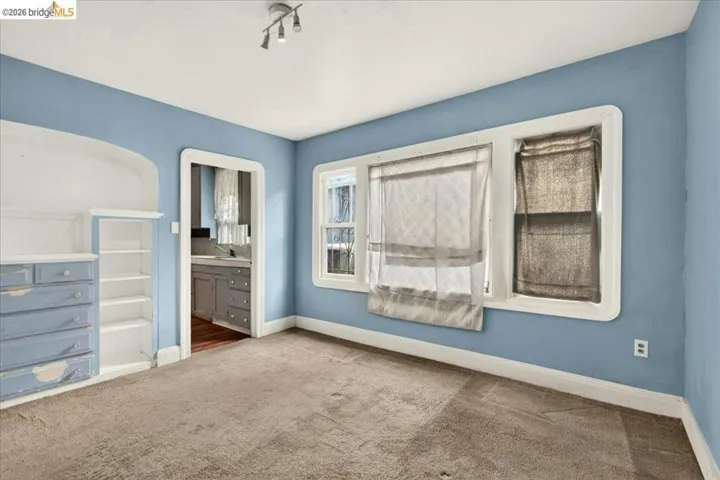 Carpeted interior space featuring light blue walls and white trim
