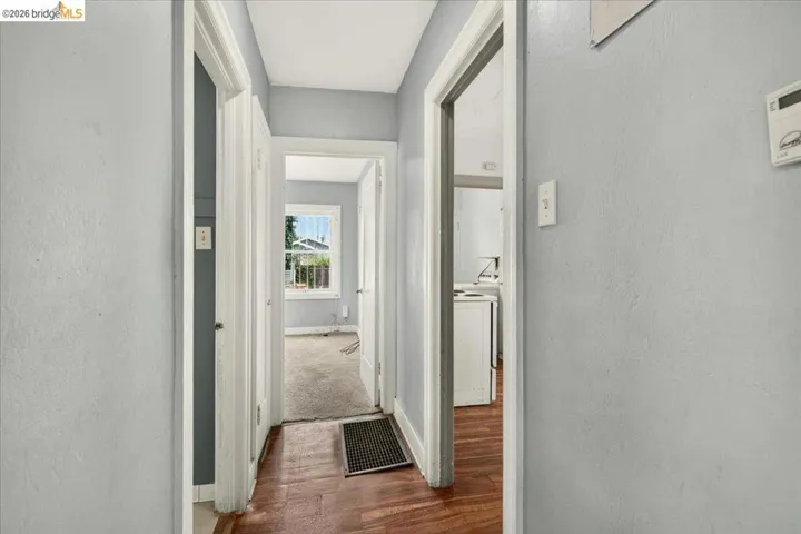 Hallway with wood-finish flooring, light grey walls, and white trim