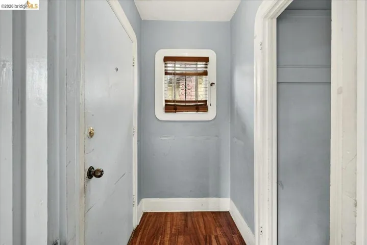 Hallway featuring wood-finish flooring and a white trim baseboard