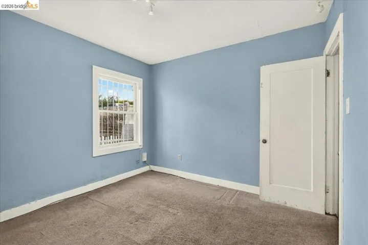 Room featuring a single window with white trim, light blue walls, and a white door