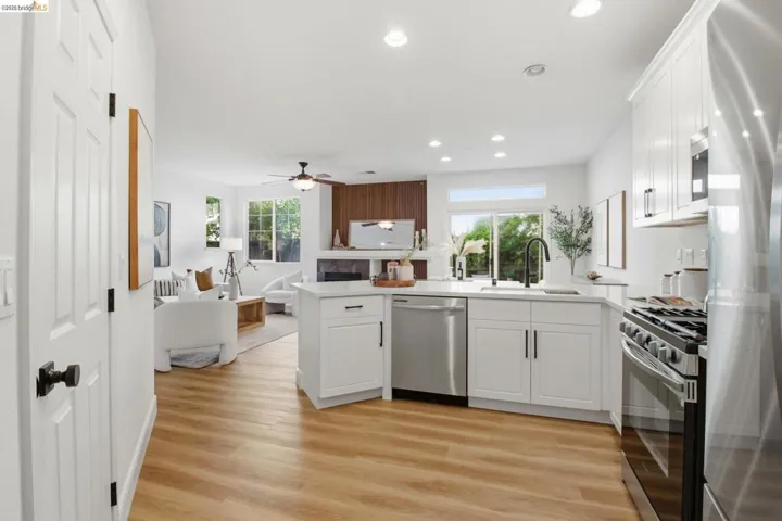 Open-concept kitchen featuring wood-finish flooring, white cabinetry, stainless steel appliances, and recessed lighting