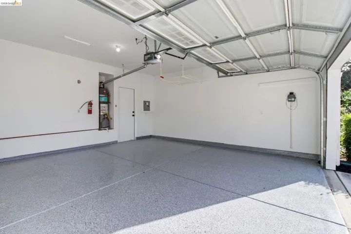 Spacious garage featuring a durable epoxy floor, white walls, and an automatic garage door opener