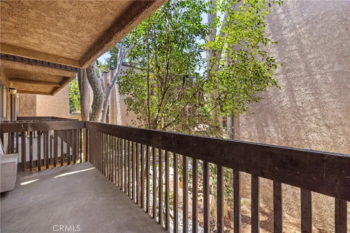 Private covered balcony overlooking mature landscaping.
