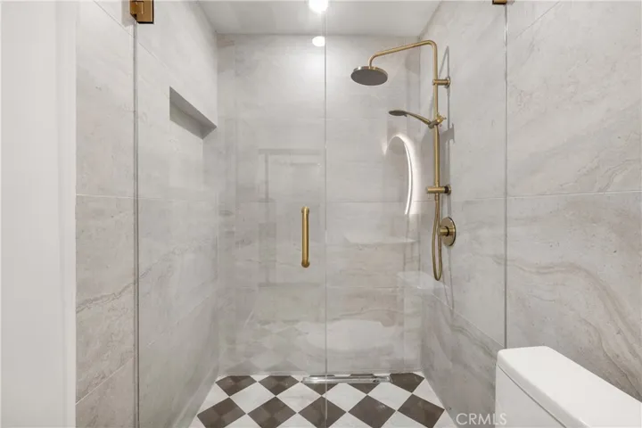 Elegant walk-in shower with premium tile and modern gold hardware.
